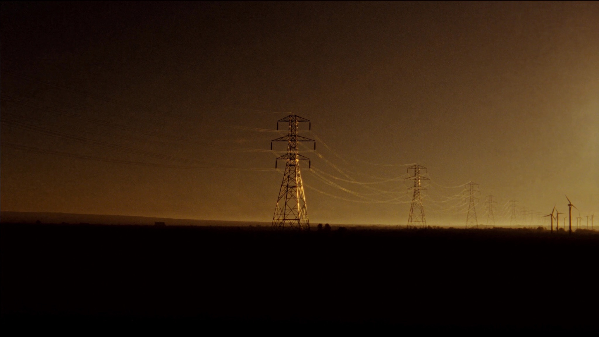 Transmission towers and wind turbines at dusk